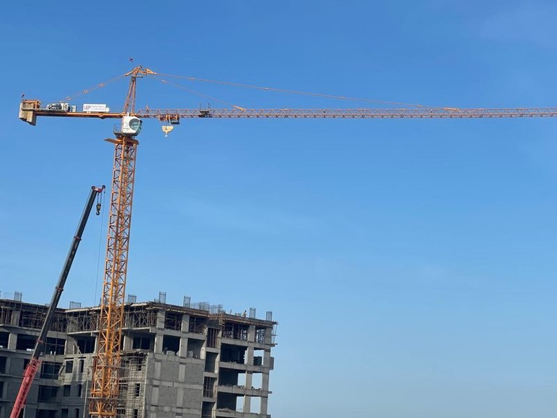 A tower crane standing beside an unfinished concrete building